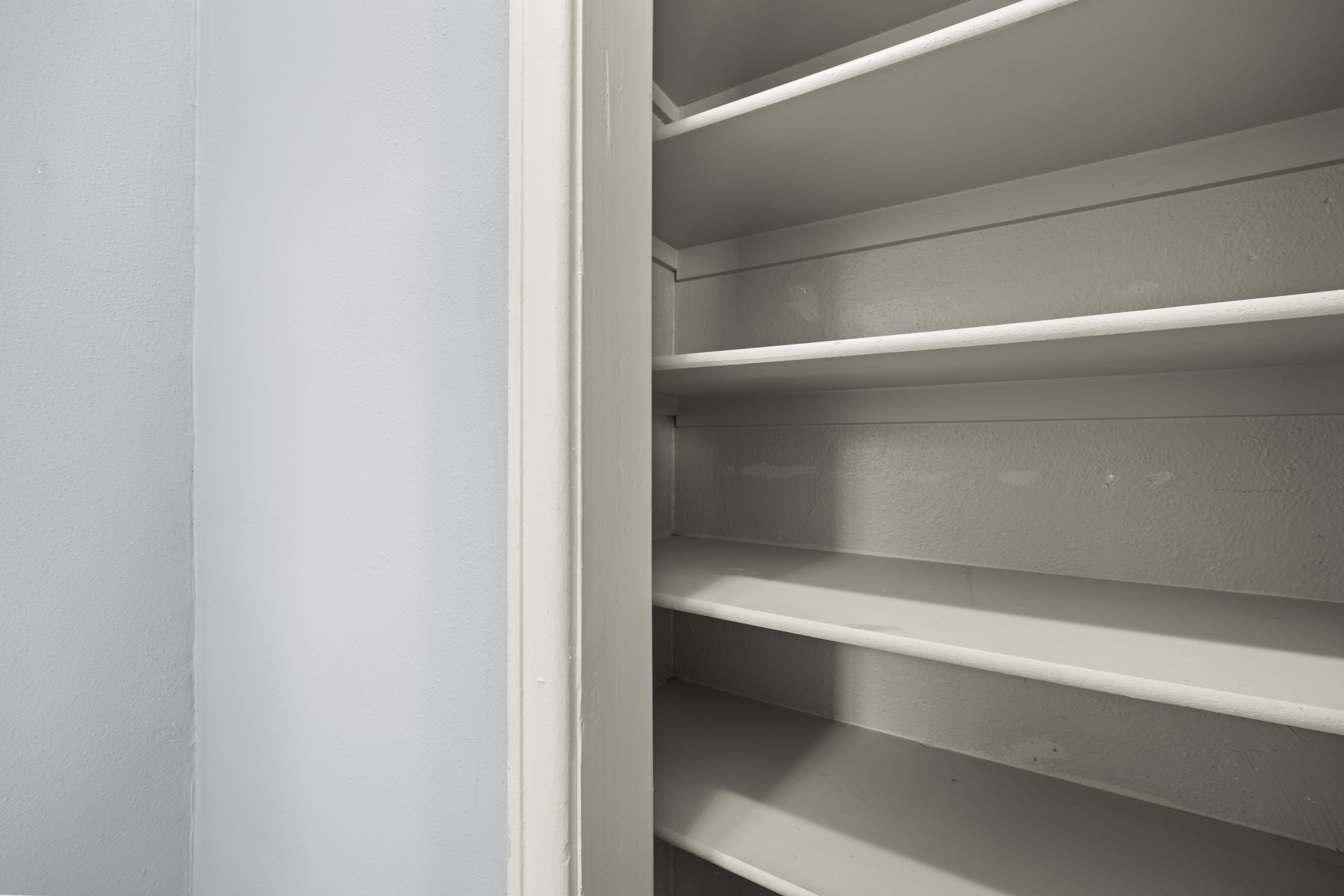 Empty white shelves in a pantry.